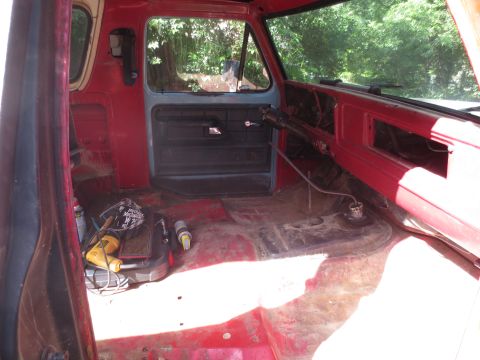 1978 Ford Bronco - The interior of a red vehicle shows tools and equipment on the floor, suggesting it is undergoing preparation or repair.