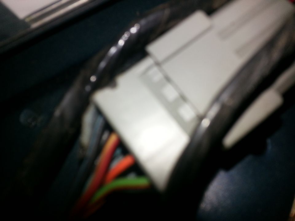 Electrical connector with red, orange, and green wires, partially obscured by black tubing