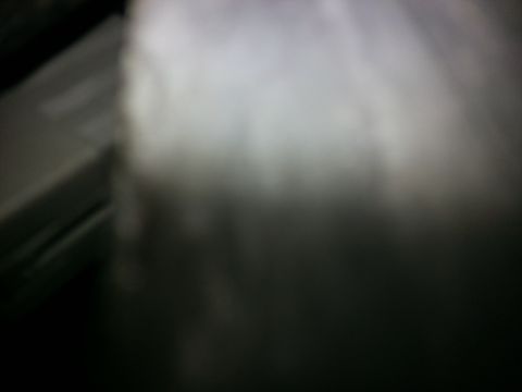 1994 Ford Bronco - A close-up of dark carpet with a blurry light area and a gray panel visible.