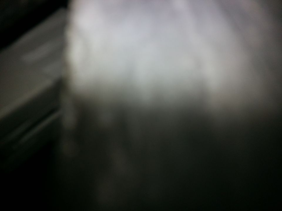 Dark carpet with a light-colored, blurry area and a partial view of a gray panel
