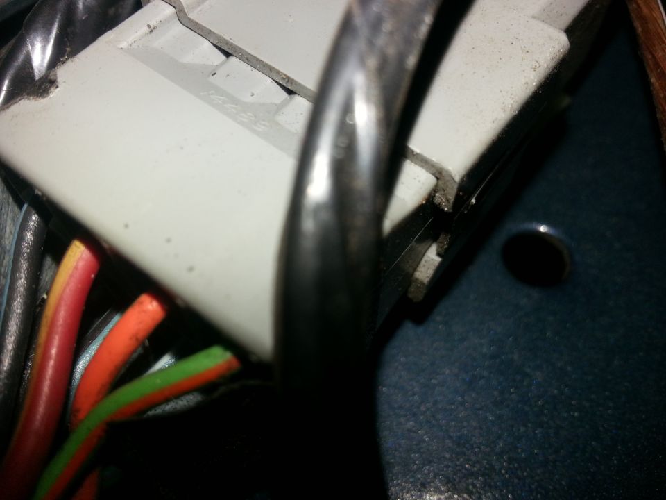 Close-up of a gray electrical connector with red, orange, and green wires