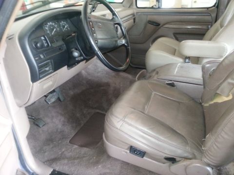 1994 Ford Bronco - The interior of a 1994 Ford Bronco, its dashboard, steering wheel, and tan leather seats.