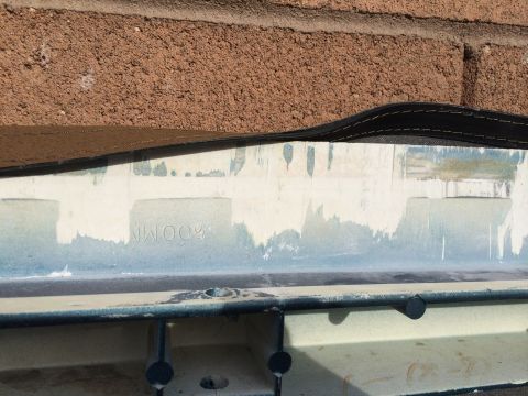 1995 Ford Bronco - A close-up view of a white plastic component with faint text visible, set against a brick wall.