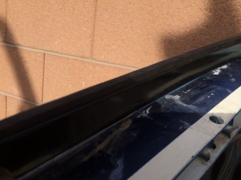 1995 Ford Bronco - Close-up of a car's door edge, showing damage and a white stripe, with a brick wall in the background.