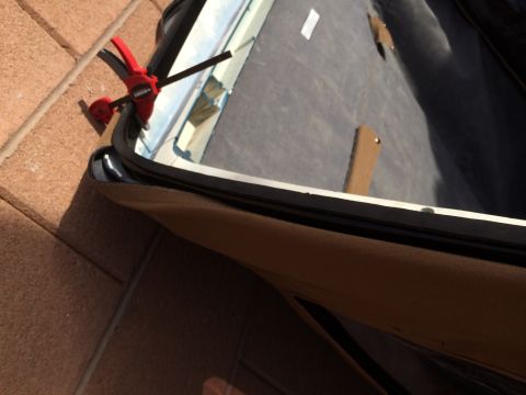 1995 Ford Bronco - Close-up view of a vehicle's soft top edge being secured with a clamp, revealing the interior fabric and construction details.