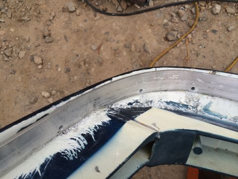 1995 Ford Bronco - Detail of a damaged vehicle body panel, showing metal and paintwork.