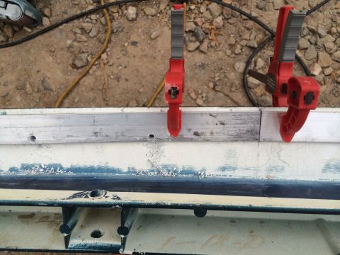 1995 Ford Bronco - A close-up of a vehicle body panel being worked on, with clamps securing a metal strip.
