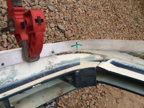 1995 Ford Bronco - A close-up view of a damaged vehicle bumper section with repair markings and a clamp attached.