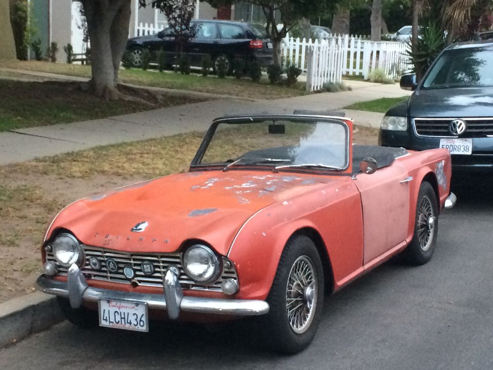 Orange Triumph TR4 convertible parked on street, California license plate 4LCH436