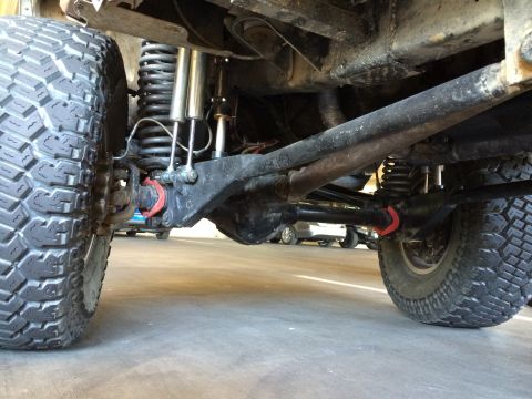 1995 Ford Bronco - The undercarriage of a modified 4x4 vehicle is visible, with focus on the suspension and drivetrain components.
