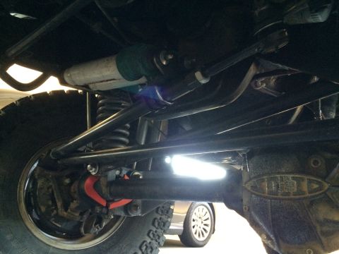1995 Ford Bronco - The underside of a vehicle is shown, with suspension and drivetrain components visible, and another car in the background.