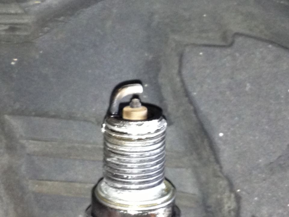 Close-up of a spark plug with white deposits on the threads