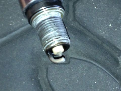 1961 International Scout 800 - A spark plug, likely from an engine, shows signs of wear and fouling.