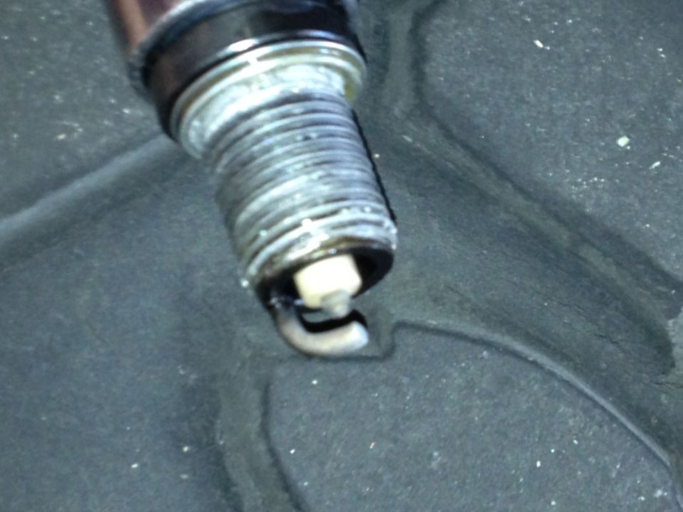 Close-up of a used spark plug with visible fouling and wear on the electrode