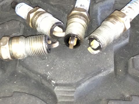 1961 International Scout 800 - A set of four used spark plugs are shown, with visible wear on the electrodes.