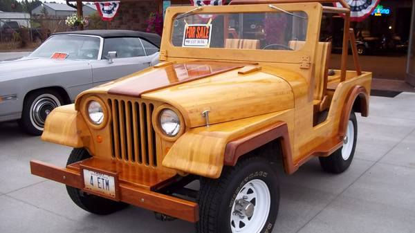Custom wooden Jeep CJ with a "FOR SALE" sign in the windshield, parked next to a silver convertible