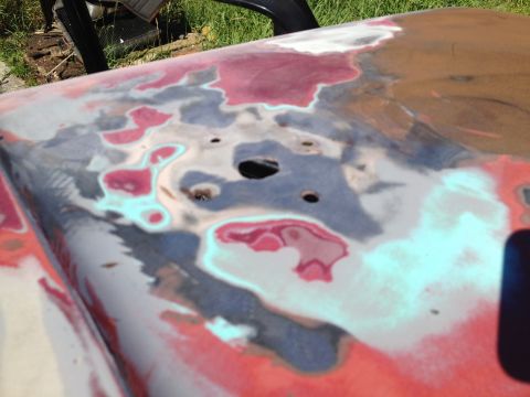 1978 Ford Bronco - A car hood shows areas of exposed metal and body filler, indicating repair work.