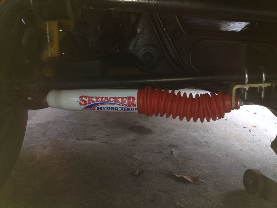 Skyjacker Hydro 7000 steering stabilizer with red accordion boot mounted under a vehicle