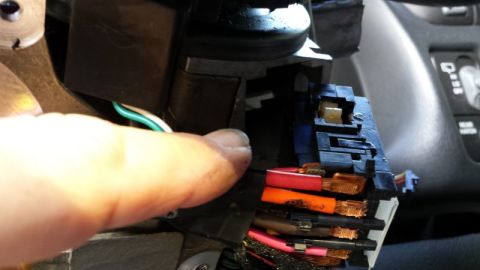 2000 GMC Jimmy - A close-up view shows a vehicle's wiring harness and connectors, with a hand reaching towards them.