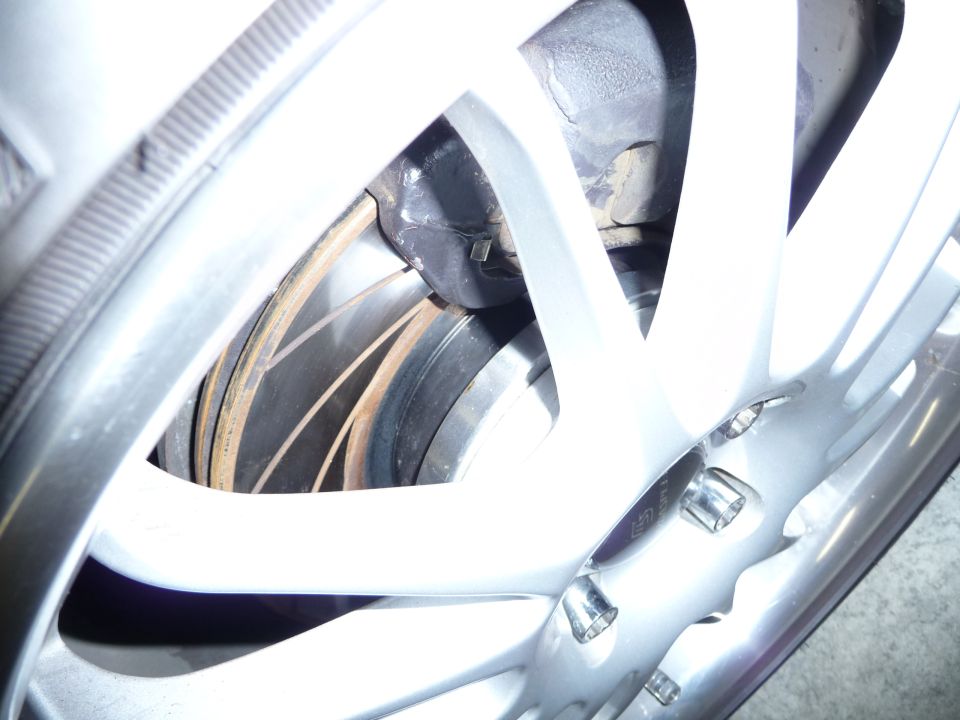 Close-up of a silver alloy wheel with a vented brake rotor and caliper visible