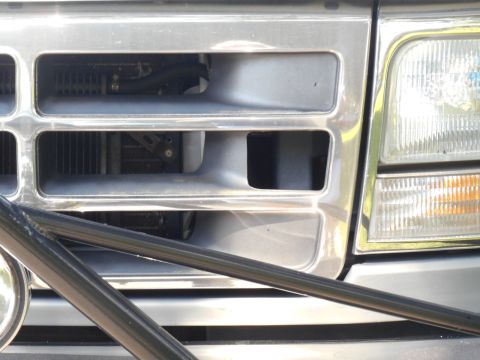 1994 Ford Bronco - Close-up of a 1992 Ford F-Series truck's grille and headlight assembly, partially obscured by a bull bar.