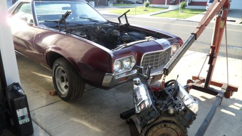 1972 Ford Ranchero - A Ford Ranchero is parked with its engine removed and suspended by an engine hoist.