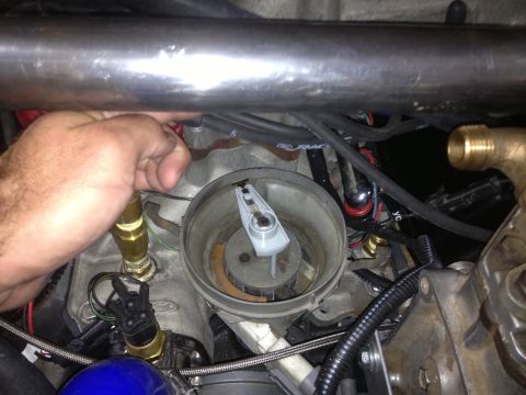 1961 International Scout 800 - Close-up of an engine's distributor cap with a hand reaching in to make an adjustment.