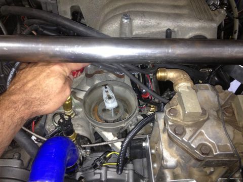 1961 International Scout 800 - A hand is seen adjusting a red cap on a distributor, surrounded by various engine components and wiring.