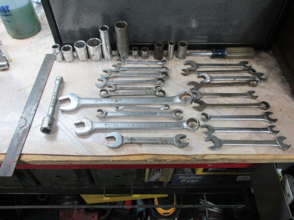 wrenches and sockets laid out on a surface, with a ruler and screwdriver
