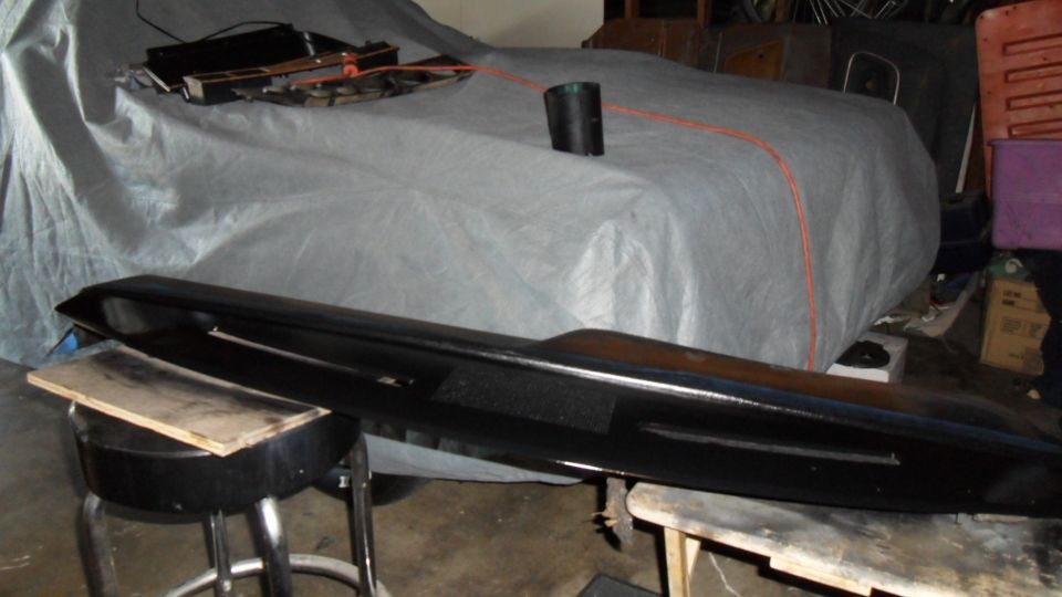 car covered with a gray tarp, with a black part in the foreground