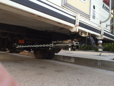 1997 Dodge 3500 - Close-up view of a trailer hitch extension and chains on a camper's undercarriage.