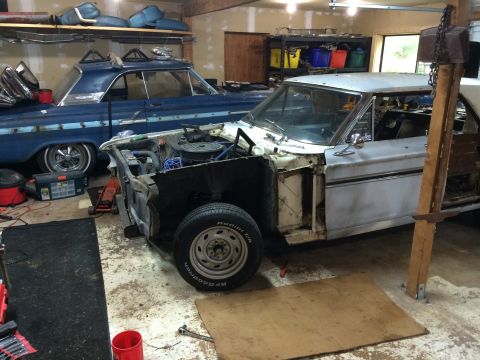 1964 Ford Fairlane - A garage scene with two classic cars, one undergoing repairs and the other parked behind it.