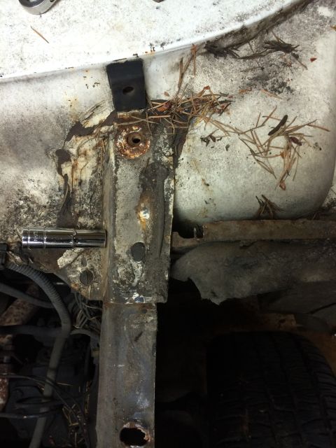 1964 Ford Fairlane - The vehicle's frame shows significant rust and deterioration, with a socket wrench still attached to a bolt.