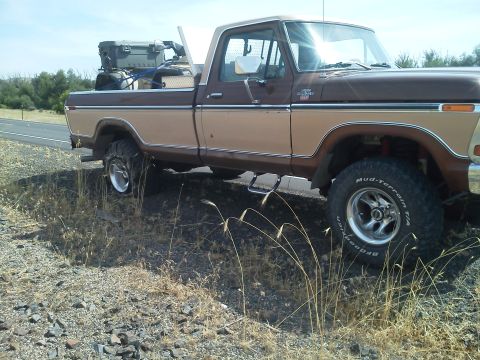 1979 Ford F-150 - This two-tone pickup truck, identified as a 1979 Ford F-150, is parked on a roadside with items secured in its bed.