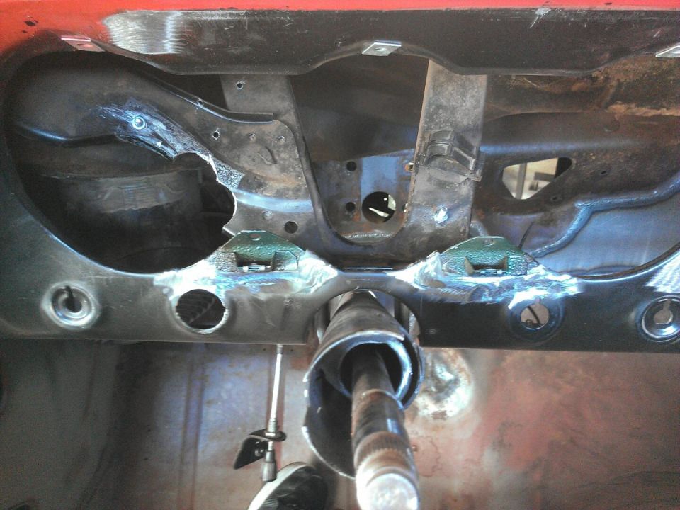 Interior firewall area of a car with steering column visible. Some welding has been done