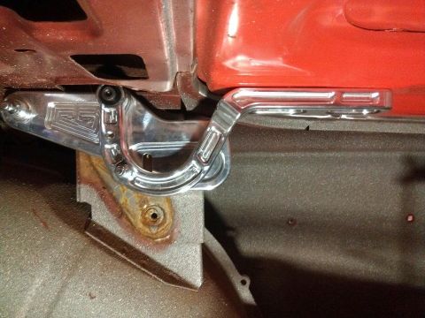1964 Ford Fairlane - Close-up of a custom hood hinge with an engraved logo, showing polished metal and painted surfaces.