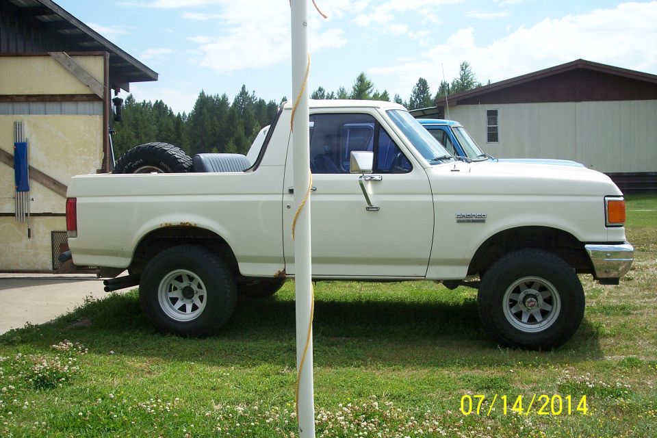 White 1990 Ford Bronco side view with spare tire in bed