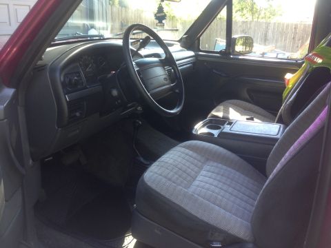 1992 Ford F-150 - Interior of a truck or SUV showing a gray cloth bench seat with fold-down center console and dark dashboard.