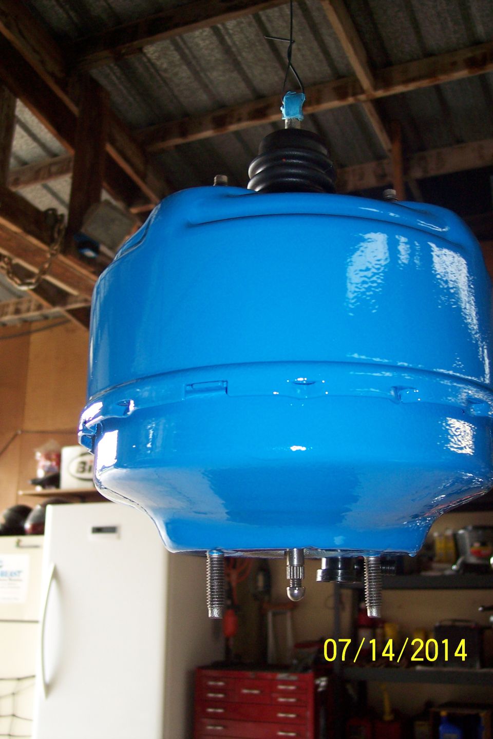 Blue brake booster hanging from ceiling, with date 07/14/2014 and SUPERMOTORS.NET watermark