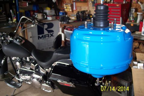 1978 Ford Bronco - A blue brake booster is shown in front of a motorcycle, with garage shelves in the background.
