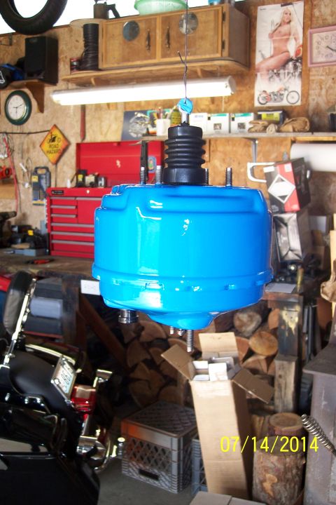 1978 Ford Bronco - Blue brake booster hanging in a garage, with a motorcycle poster on the wall.
