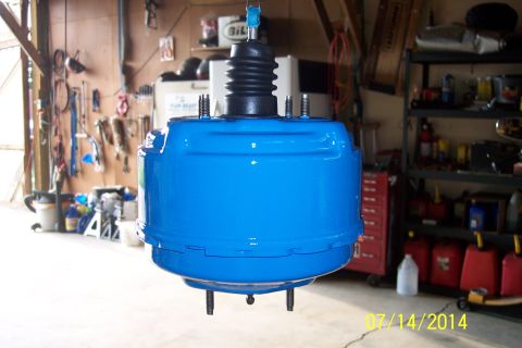 1978 Ford Bronco - A freshly painted blue brake booster is suspended in a workshop environment.