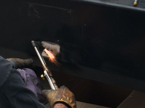 1997 Dodge 3500 - A torch is used to repair a damaged black surface, indicating ongoing maintenance or restoration work.