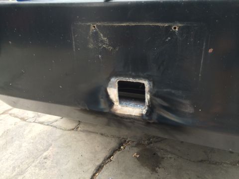 1997 Dodge 3500 - Close-up of a black bumper showing a modified square opening and signs of repair.