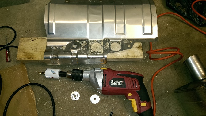 Metal undercarriage part with drill and hole saw on concrete floor