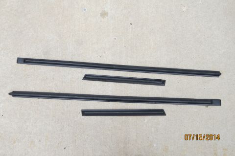 1985 Volkswagen Jetta - Four black rubber trim pieces, likely for car doors, are shown on a concrete surface.