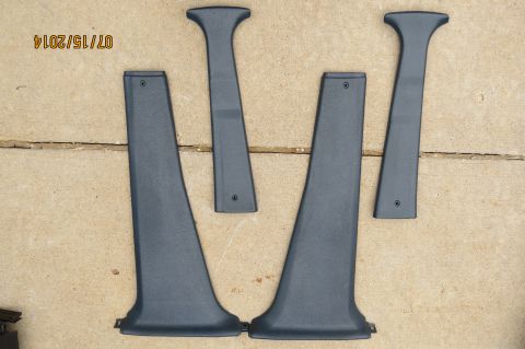1985 Volkswagen Jetta - Four dark gray plastic interior trim pieces are displayed on a concrete surface.