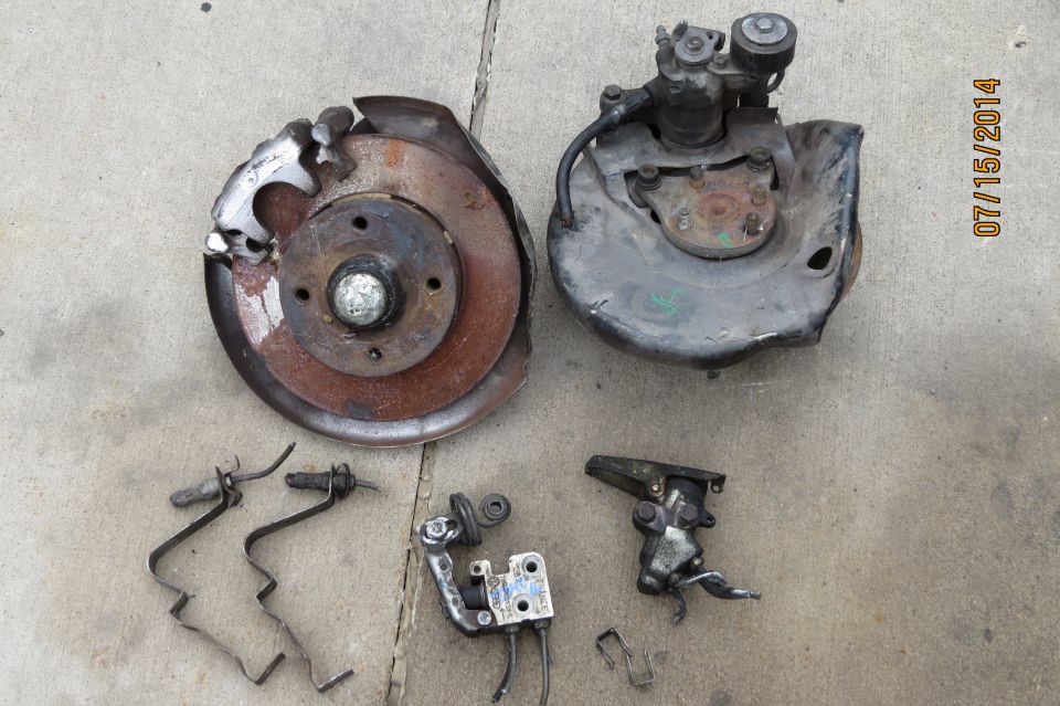 Brake rotor, caliper, and hub assembly parts laid out on concrete