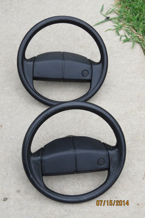 1985 Volkswagen Jetta - Two Volkswagen steering wheels are displayed on a concrete surface with grass in the background.