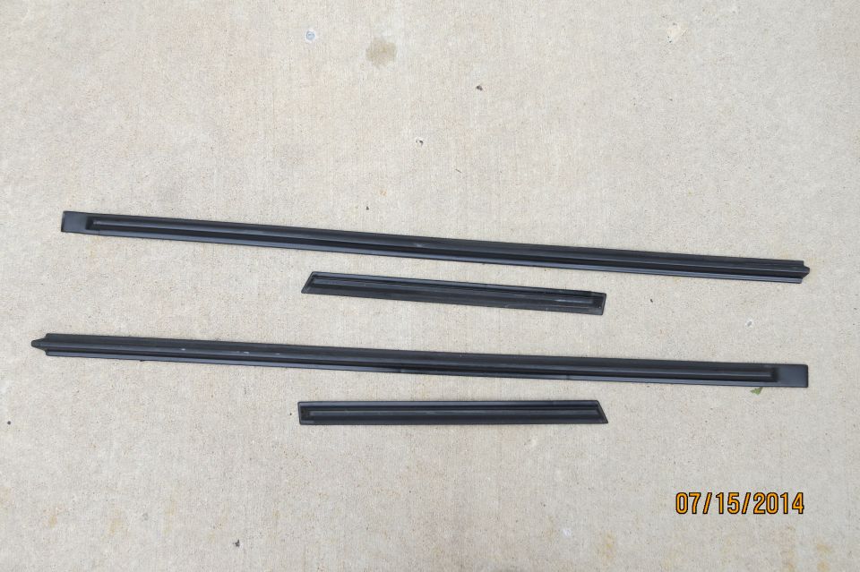 Four black rubber trim pieces laid out on a concrete surface